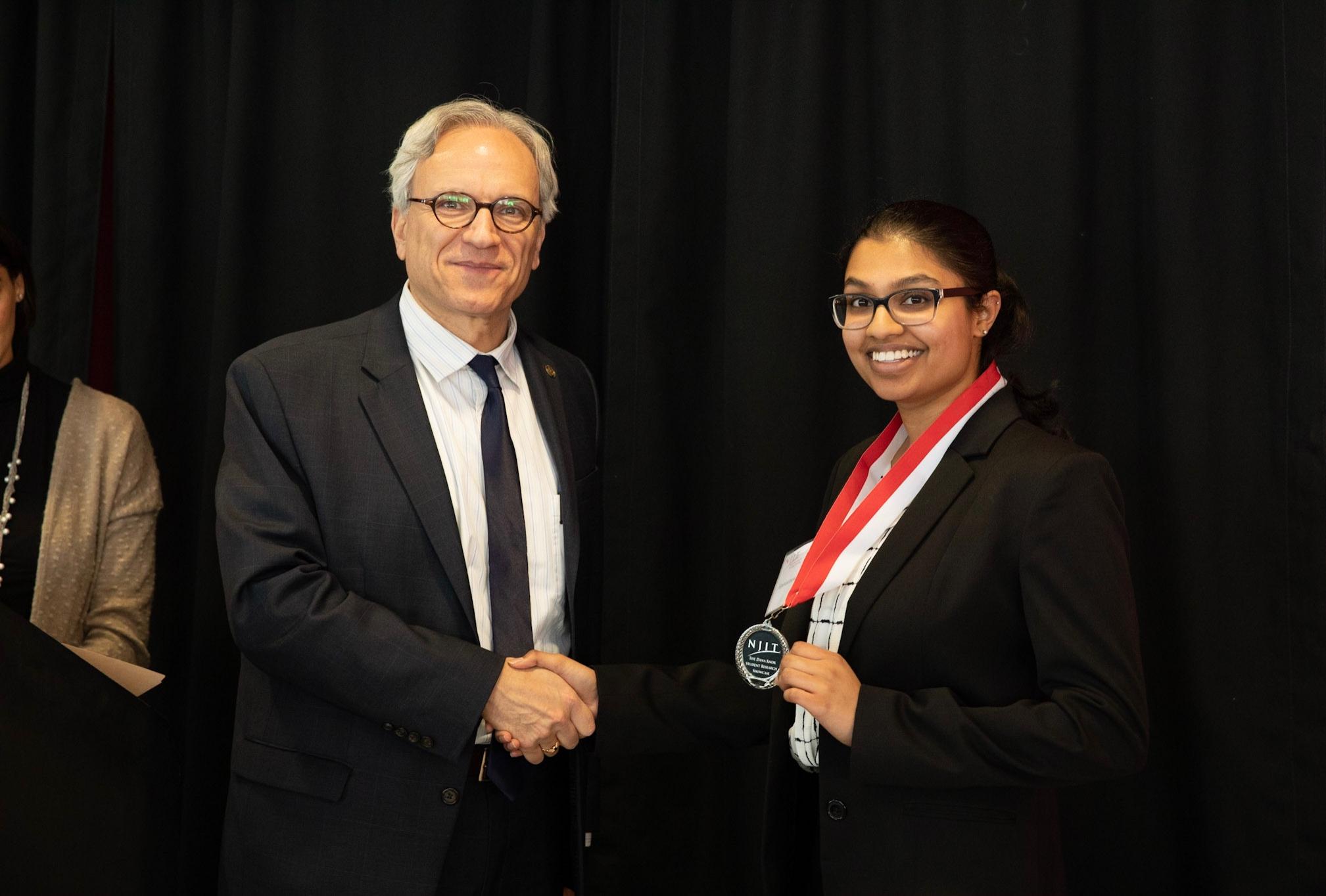 Biology sophomore and student at Albert Dorman Honors College, Geetasravya Vegunta, collects her award alongside NJIT Provost Fadi P. Deek.