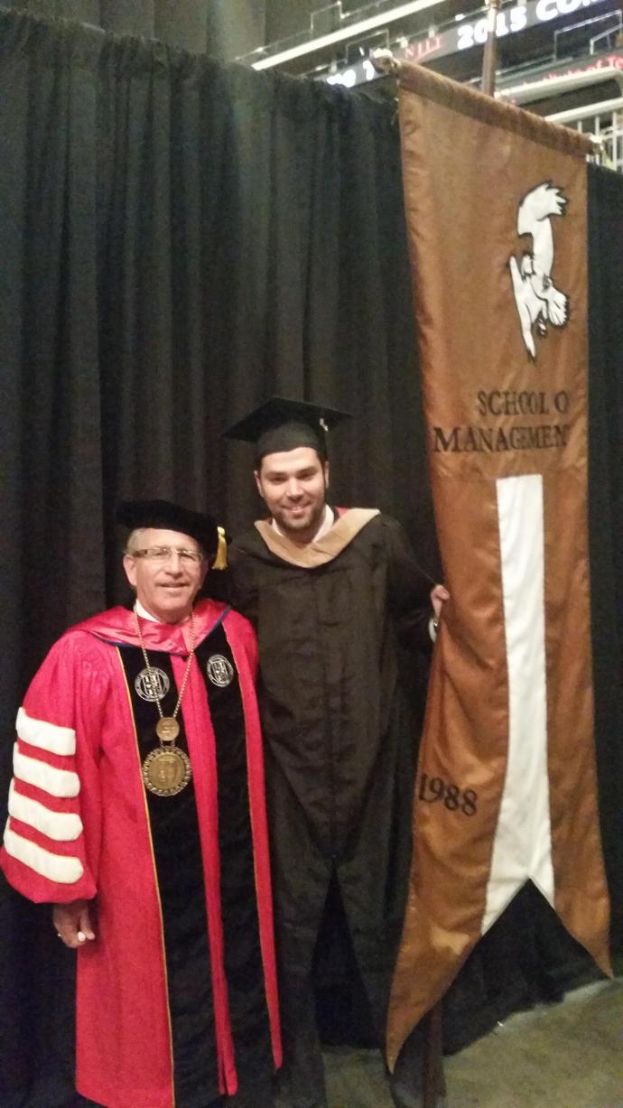 Rogerio Henriques (right), here with NJIT President Joel Bloom, carried the Martin Tuchman School of Management gonfalon at the 2015 graduation ceremony.