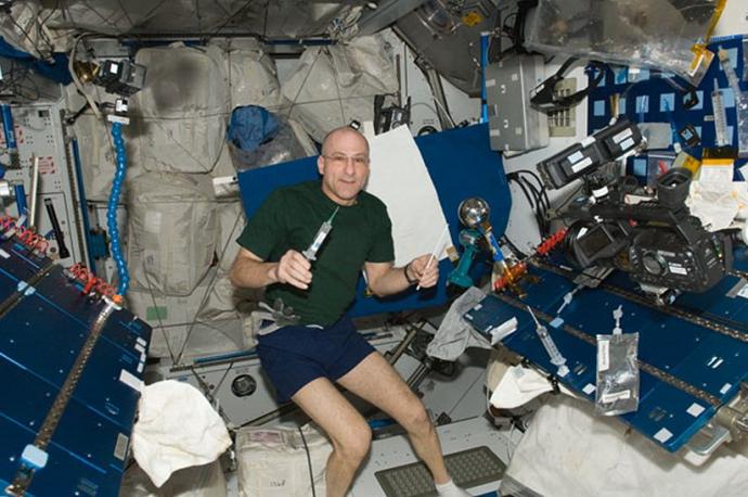 Astronaut Donald R. Pettit on board the International Space Station. To the right is the Van de Graaff generator that he improvised with Legos and used to electrify water droplets and gain new, important knowledge about Taylor cones in collaboration with 