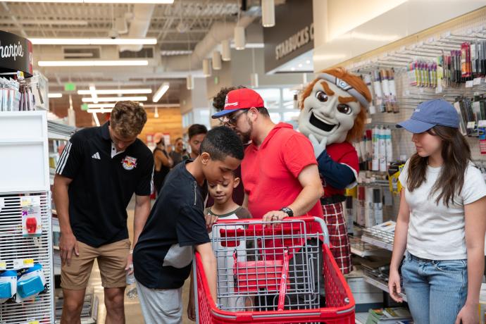 Matthew Hernandez (center) with his father Peter Hernandez and little brother picking out items with Red Bulls forward, Tom Barlow.