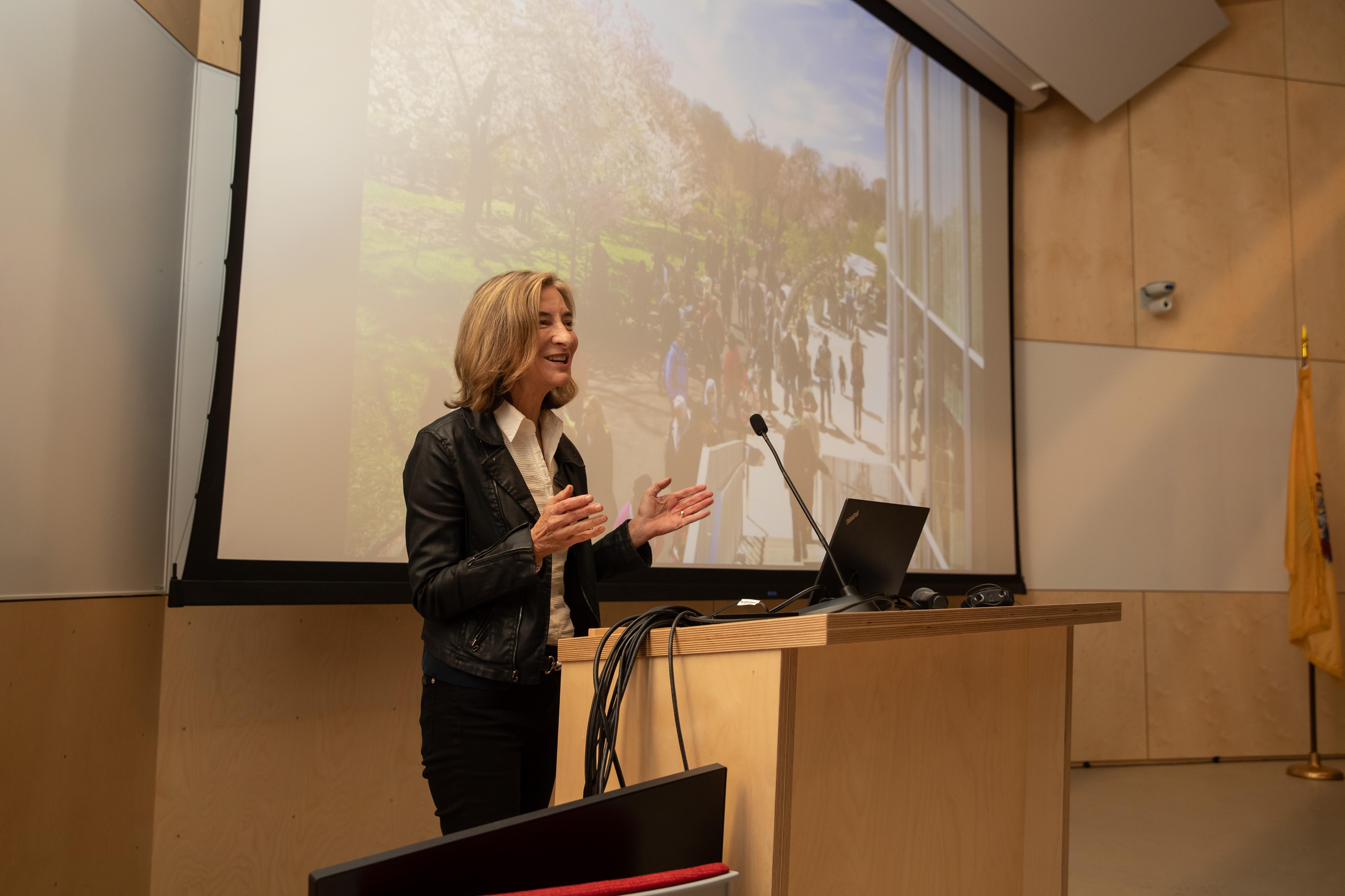 Marion Weiss gives a lecture to a room full of students, faculty and alumni. 
