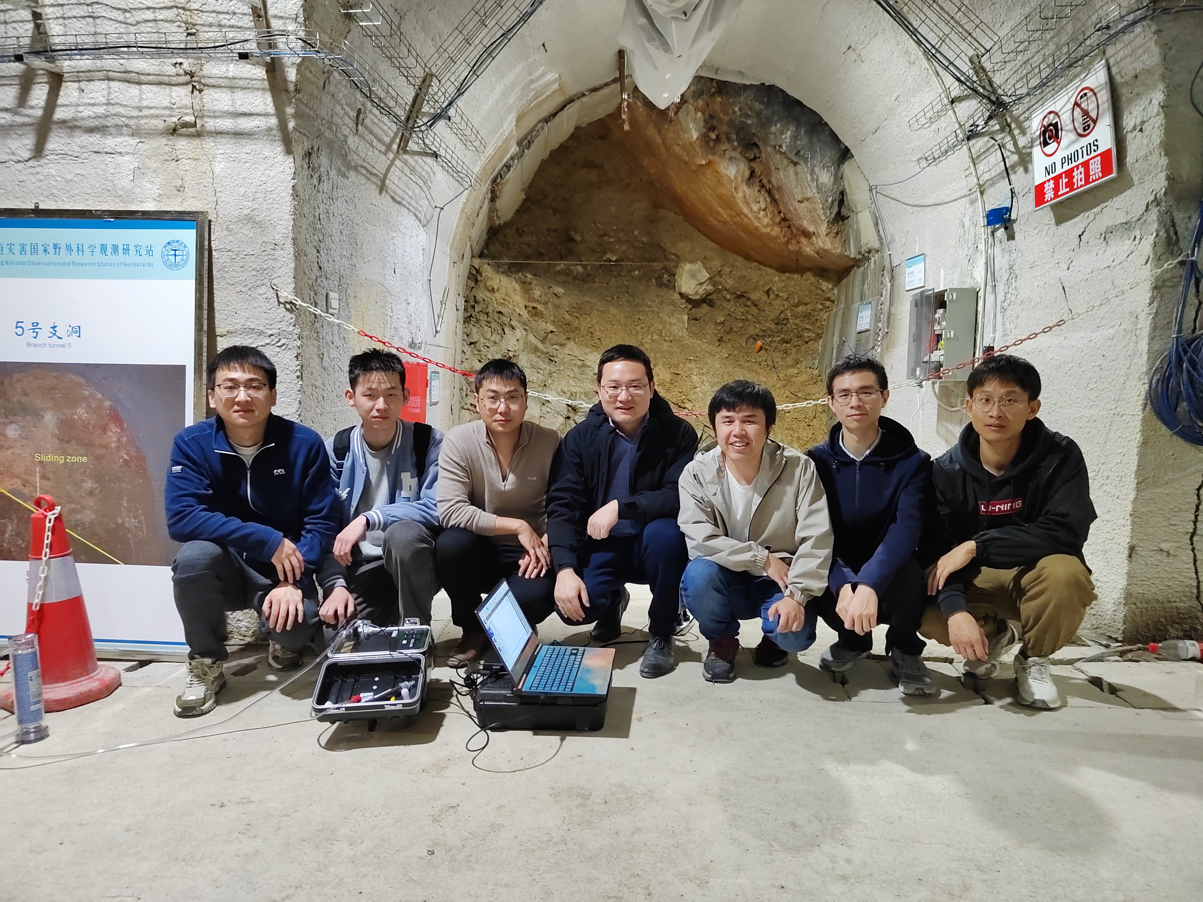 Seven people kneel in front of a tunnel partially filled with rubble. Study co-authors (from right to left) Fushuo Gan, Rong Mao (co-first author), Xin Luo (corresponding author) and Jia-Qing Zhou (co-first author); and researchers Haibing Yu, Zhi-Jie Che and Shuai Miao, photographed during work on a geohazards monitoring system in the Three Gorges Reservoir Region in China. 