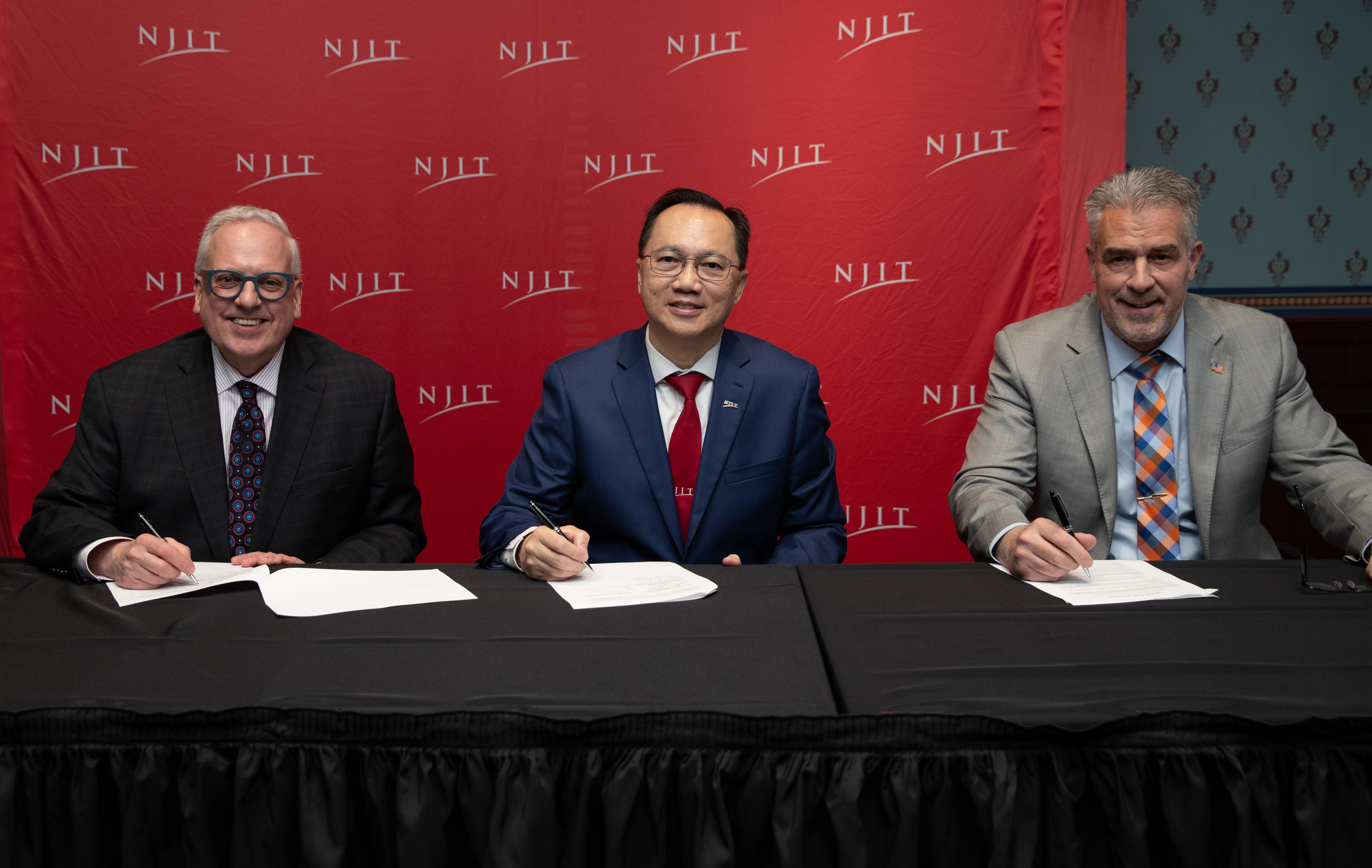 Christopher Reber, Teik Lim, and John Capo sign the agreement