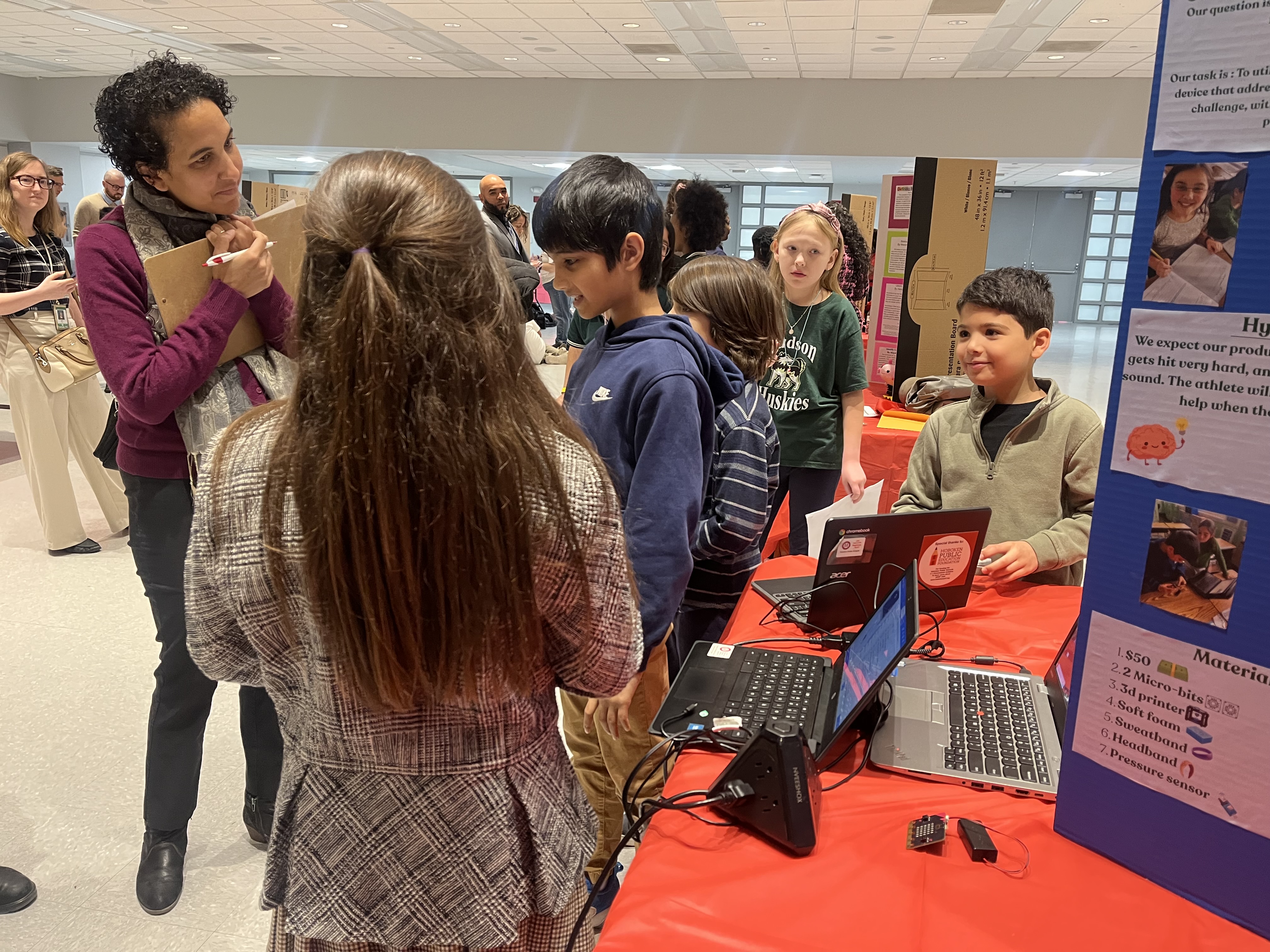 A volunteer judge reviews a presentation on concussion prevention by the "eSTEM Smarties," a team from Joseph F. Brandt Primary School in Hoboken.
