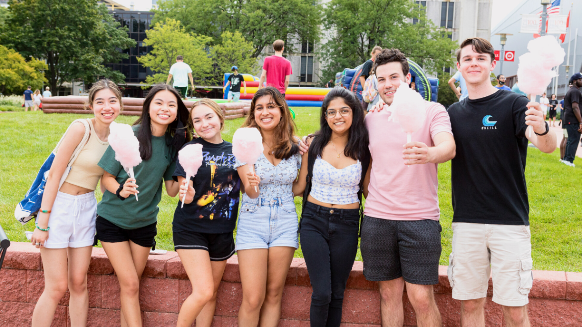 Seven NJIT students holding cotton candy on the campus green during move-in weekend
