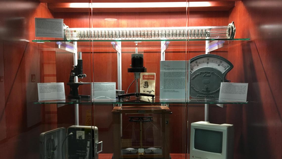 NJIT Distributed Technology Museum’s first 7-piece exhibit displayed in Fenster Hall (Top Shelf: York-Scheibel Column; Middle Shelf, Left: 1947 Bausch & Lomb optical microscope; Middle Shelf, Center: Brookefield Viscometer; Middle Shelf, Right: Weston Sta