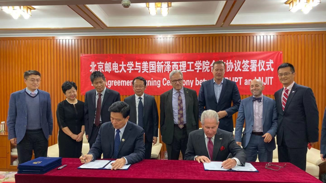 Jianyong Qiao, BUPT president (seated left), and Joel S. Bloom, NJIT president (seated right), sign agreements between the two universities as faculty and staff look on.