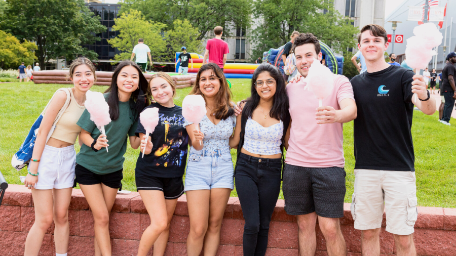 Seven NJIT students holding cotton candy on the campus green during move-in weekend
