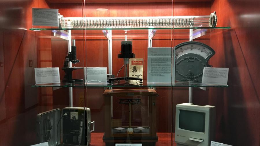 NJIT Distributed Technology Museum’s first 7-piece exhibit displayed in Fenster Hall (Top Shelf: York-Scheibel Column; Middle Shelf, Left: 1947 Bausch & Lomb optical microscope; Middle Shelf, Center: Brookefield Viscometer; Middle Shelf, Right: Weston Sta