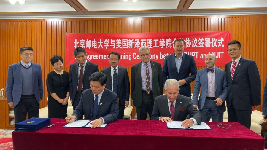 Jianyong Qiao, BUPT president (seated left), and Joel S. Bloom, NJIT president (seated right), sign agreements between the two universities as faculty and staff look on.