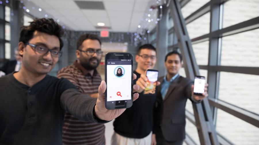 four students hold up smartphones featuring FaceDate