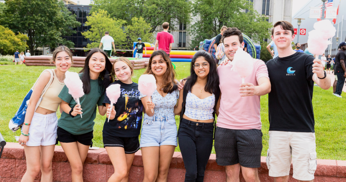 Seven NJIT students holding cotton candy on the campus green during move-in weekend