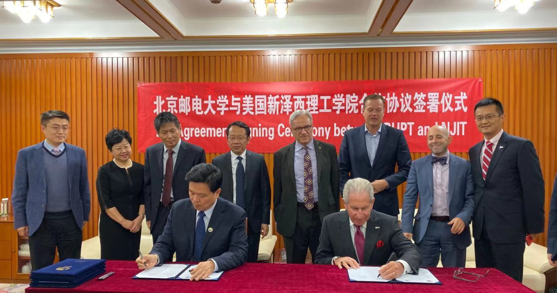 Jianyong Qiao, BUPT president (seated left), and Joel S. Bloom, NJIT president (seated right), sign agreements between the two universities as faculty and staff look on.