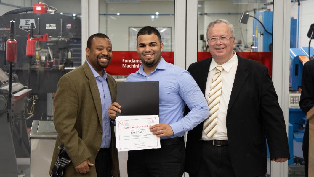 Randy Valerio, a production maintenance supervisor for a pharmaceutical company, receives his training certificate as Professor ShaQueel Dyer (left), who taught the course, and Newark College of Engineering Dean Moshe Kam (right) look on.