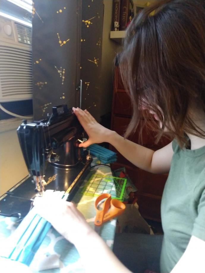 Laura Gould (above), a Dorman Scholar and architecture student, is sewing protective masks. (Below) She wears one of the 1,000 she plans to make.