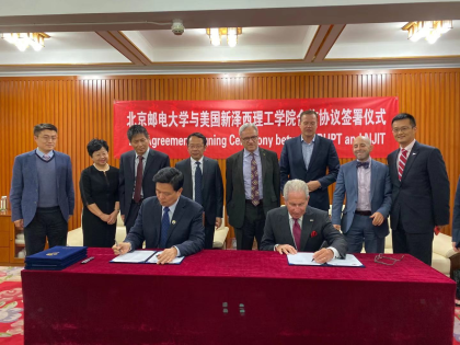 Jianyong Qiao, BUPT president (seated left), and Joel S. Bloom, NJIT president (seated right), sign agreements between the two universities as faculty and staff look on.