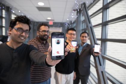 four students hold up smartphones featuring FaceDate