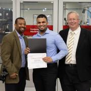 Randy Valerio, a production maintenance supervisor for a pharmaceutical company, receives his training certificate as Professor ShaQueel Dyer (left), who taught the course, and Newark College of Engineering Dean Moshe Kam (right) look on.