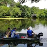 Surveying engineering technology students and Bert Wyness, instructor, traverse the lake in Newark's Branch Brook Park to perform a bathymetric survey.